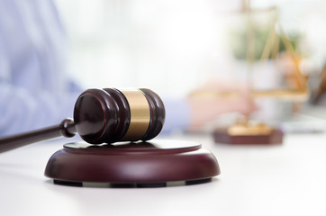 Wooden gavel, working lawyer in background.