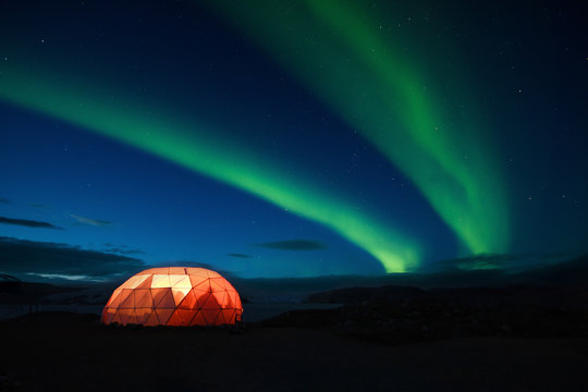 Aurora boreale con tenda illuminata, Groenlandia