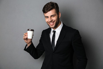 Young successful businessman enjoing his morning coffee, looking at camera