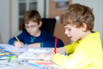 Two little kids boys at home making homework.