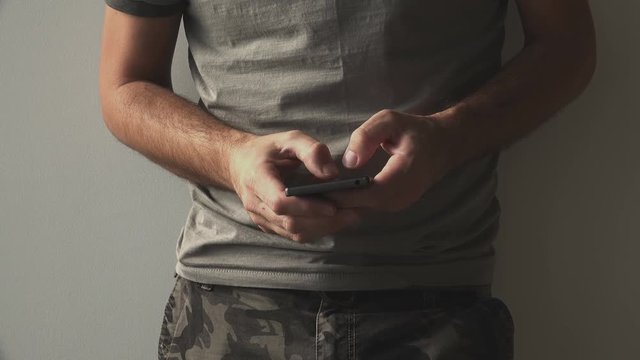 Military soldier using smartphone for texting. Army officer typing SMS text message on mobile phone.