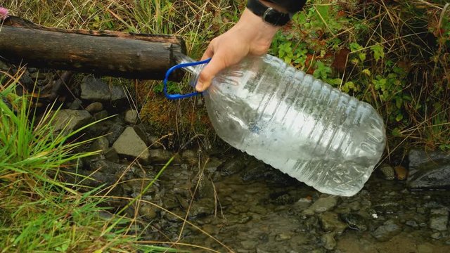 mountain spring. draw water in a big plastic container