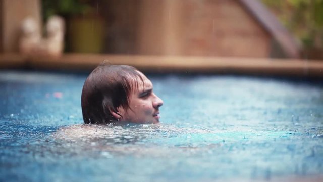 Wet caucasian happy man gets rained enjoyes while swimming in pool on vacation. 1920x1080