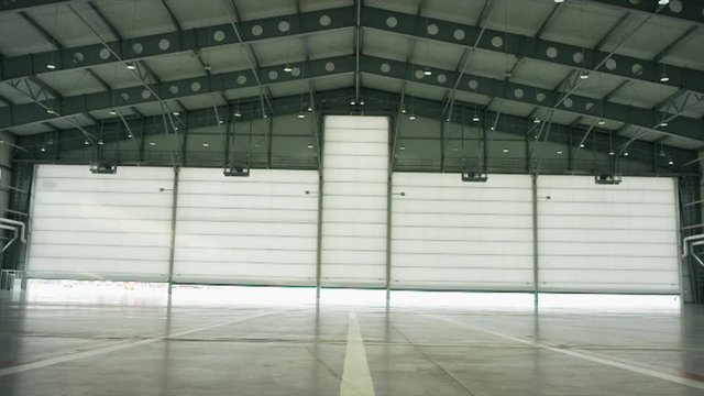 Big modern aircraft hangar with big gate at sunny summer day. Gate of the aircraft hangar