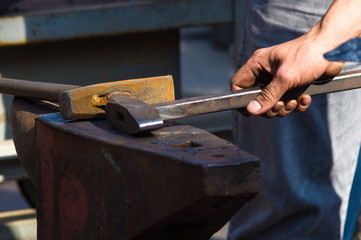 blacksmith performs the forging of hot glowing metal on the anvil