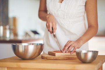 Mixed race woman preparing salmon for lunch while standing in modern kitchen
