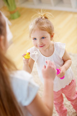 Obraz na płótnie Canvas Mädchen hilft kleiner Schwester beim Seifenblasen