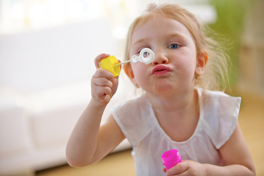 M&auml;dchen pustet Seifenblasen im Kinderzimmer