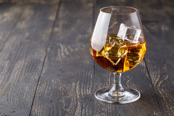 glass of whiskey with ice on a wooden background