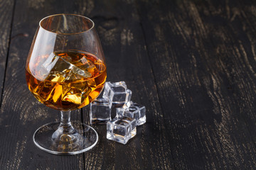 glass of whiskey with ice on a wooden background