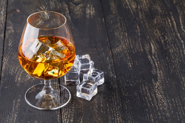 Glasses of whiskey on wood background.