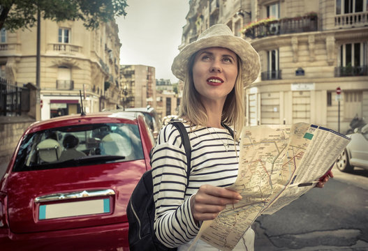 Woman tourist on the street in Paris, look on map under sunlight