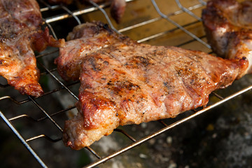 Close up view of juicy pork steak cooked on an open flame grill..