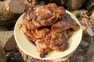 Juicy pork steaks cooked on an open flame grill on big white plate..