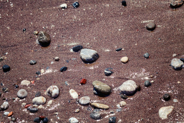 Small multicolored stones on a sandy beach