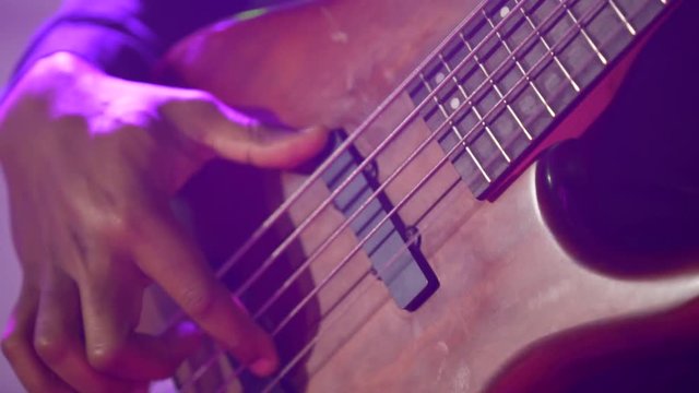 Acoustic six-string guitar. The black man plays the guitar. Club lighting. Very large plan. Macro shooting.