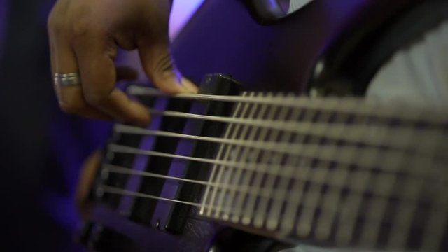 Acoustic six-string guitar. The black man plays the guitar. Club lighting. Very large plan. Macro shooting.