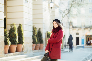 Holidays, winter, people concept - Stylish fashion girl in red coat and black beret, walking in old town.