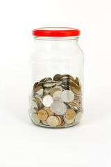 Close up coins in glass jar on white table. Isolated on white background.