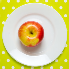 ripe red-yellow apple on a white plate. square image