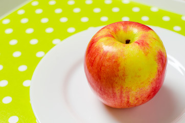 ripe red-yellow apple on a white plate