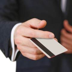 Businessmen holding credit card proposing it to you. Hand in black suit holds out a blank grey credit card. Close up.