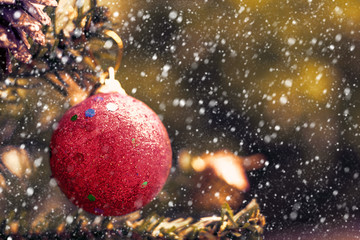Red Christmas ball decoration hanging on tree with snow effect and added color filter