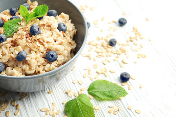 Tasty oatmeal with berries in bowl on table