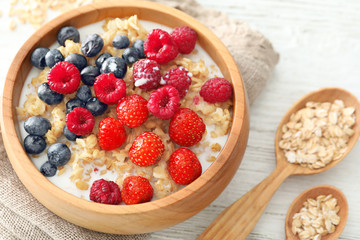 Tasty oatmeal with berries in bowl on table