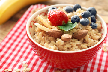 Tasty oatmeal with berries and fruit in bowl on table
