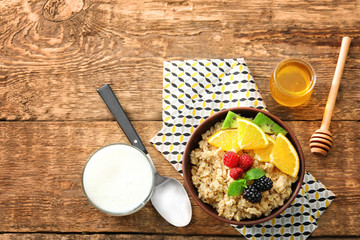 Tasty oatmeal with berries and fruit in bowl on table