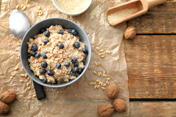 Tasty oatmeal with berries in bowl on table
