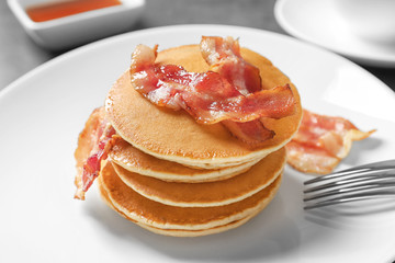 Tasty pancakes with bacon on table, closeup