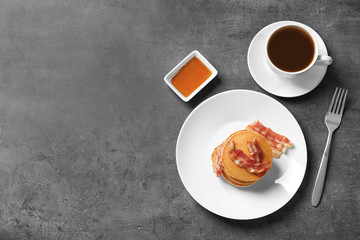 Tasty pancakes with bacon and cup of coffee on plate