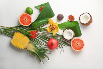 Composition with tropical leaves and exotic fruits on light background