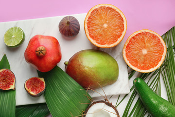 Composition with tropical leaves and exotic fruits on color background