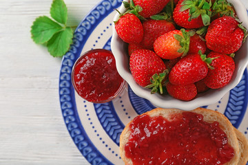 Bread with strawberry jam and bowl of fresh berries on plate
