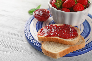 Bread with strawberry jam and bowl of fresh berries on plate
