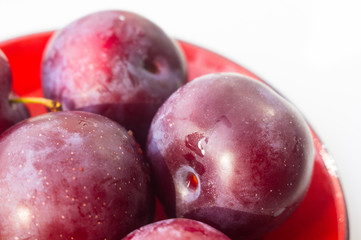 fresh plum fruit in the red saucer on white background