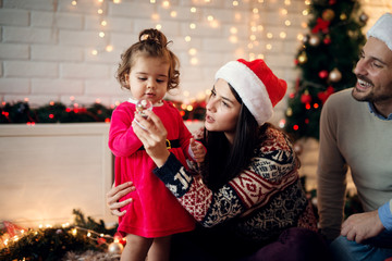 Charming cute small toddler girl playing with a toy with her parents for Christmas holidays.