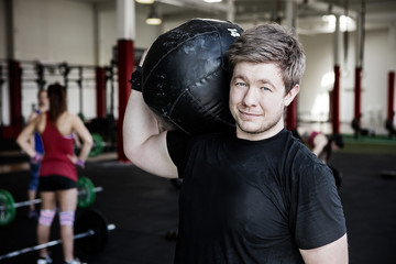 Man Carrying Medicine Ball On Shoulder In Gym