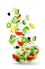 Sliced vegetables falling into bowl with salad on white background © Africa Studio