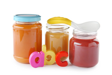 Jars with yummy baby food and spoon on white background