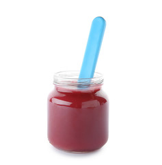 Jar with yummy baby food and spoon on white background