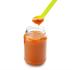 Jar with yummy baby food and spoon on white background