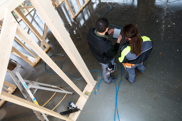 Rear View Of Workers With Digital Tablet At Site