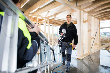 Carpenter Holding Drill Machine While Looking At Colleague Carry