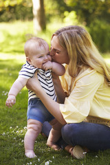 Fototapeta premium Young Mother Playing With Baby Son Outdoors In Summer Garden
