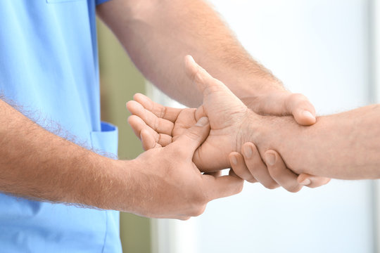 Physiotherapist giving senior man hand massage in clinic