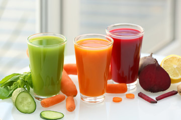 Glasses with various fresh juices and ingredients on table